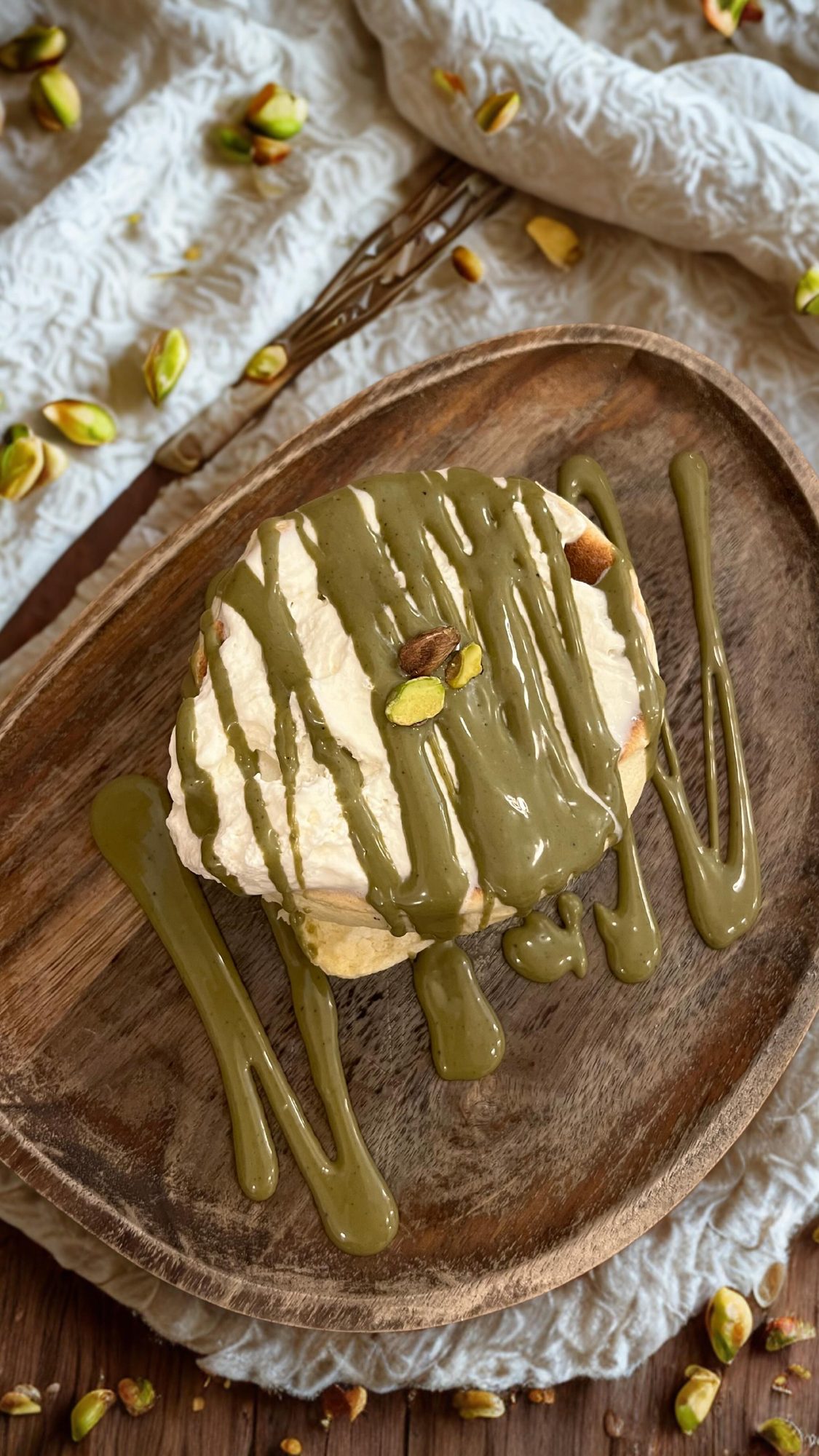 Fluffy pancake japonais nappé de matcha et pistache, sur une assiette en bois